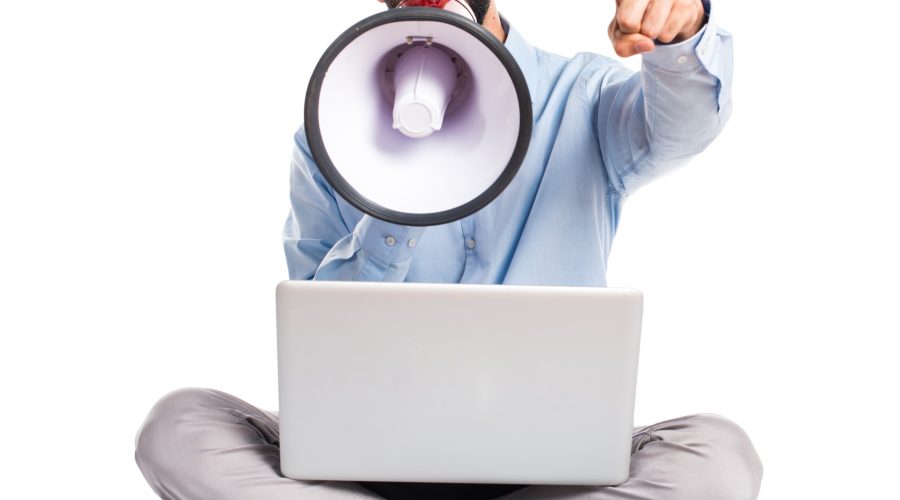 Man with laptop shouting by megaphone